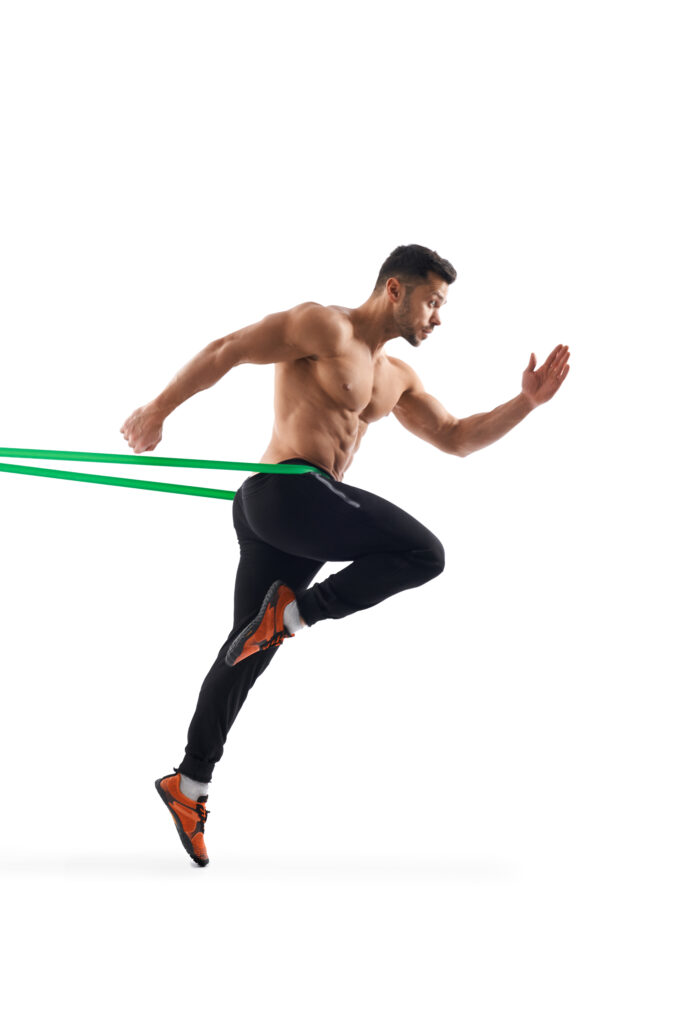 Shirtless man running in place using resistance band.